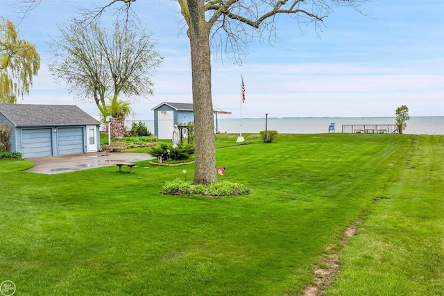 view of yard with a water view, an outdoor structure, and a garage