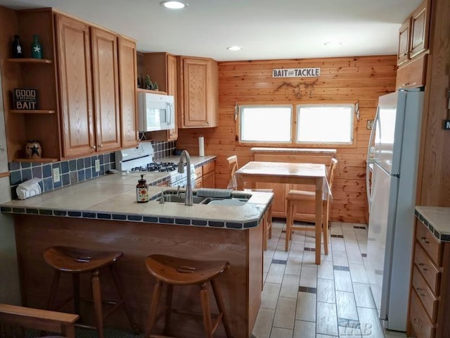 kitchen with a peninsula, open shelves, a kitchen bar, and white appliances