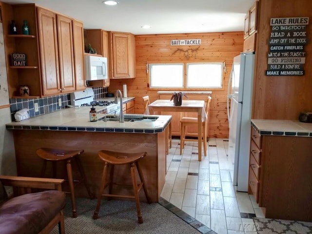 kitchen with open shelves, a peninsula, white appliances, recessed lighting, and a sink