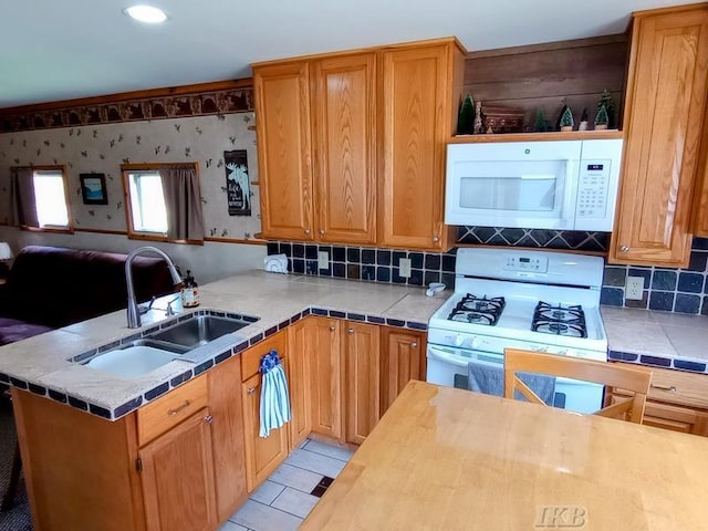 kitchen featuring a sink, white appliances, a peninsula, open floor plan, and decorative backsplash
