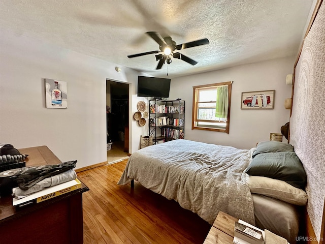 bedroom with baseboards, a textured ceiling, light wood-style flooring, and ceiling fan