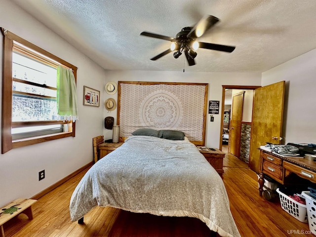 bedroom with a textured ceiling, ceiling fan, and wood finished floors