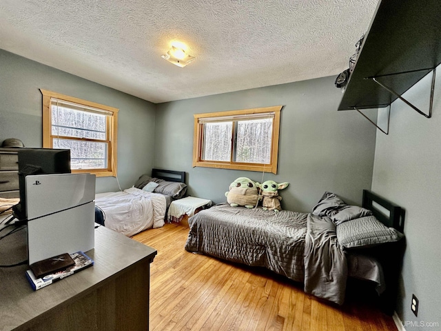 bedroom featuring a textured ceiling, multiple windows, and light wood finished floors