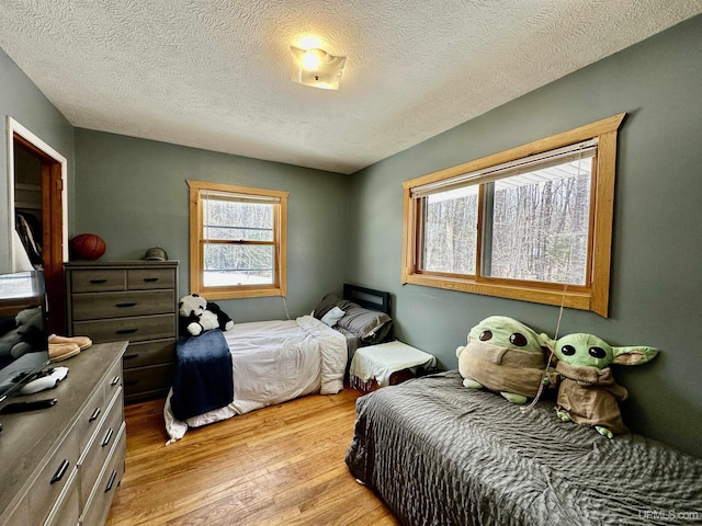 bedroom with a textured ceiling and light wood-style floors