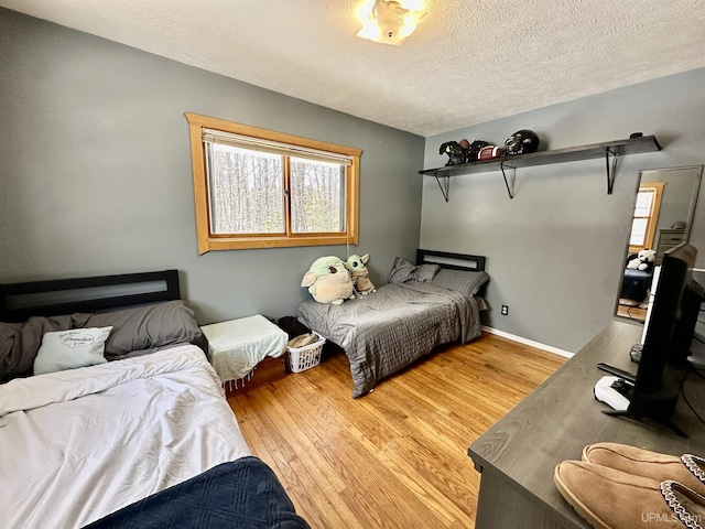 bedroom featuring light wood-style floors, a textured ceiling, and multiple windows