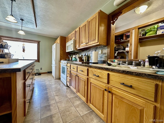 kitchen with white appliances, dark countertops, brown cabinetry, and a sink