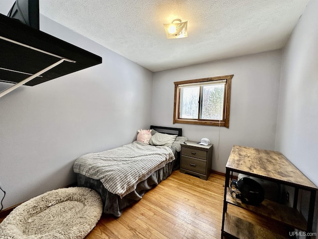 bedroom with a textured ceiling, baseboards, and light wood-style flooring