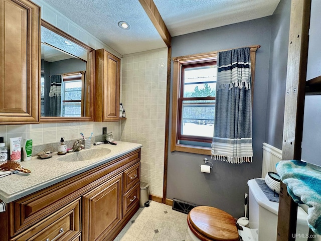 bathroom featuring a textured ceiling, visible vents, vanity, baseboards, and toilet