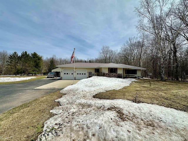 view of front of house with a garage, driveway, and metal roof