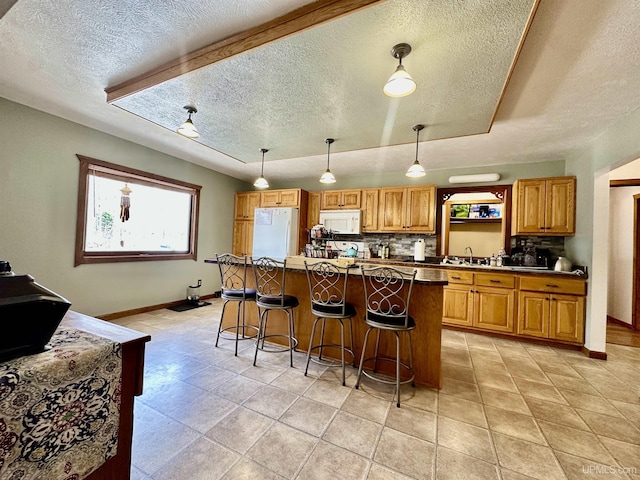 kitchen with white appliances, a textured ceiling, baseboards, tasteful backsplash, and a kitchen island