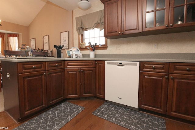kitchen featuring white dishwasher, light countertops, a peninsula, dark wood-type flooring, and vaulted ceiling