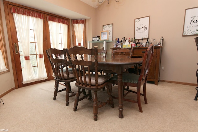 dining room with baseboards, a healthy amount of sunlight, and light carpet
