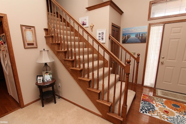 carpeted foyer with baseboards and stairs