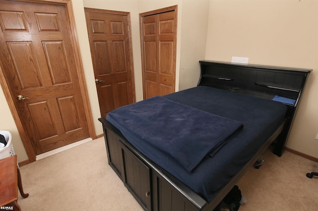 bedroom with baseboards, light carpet, and a closet