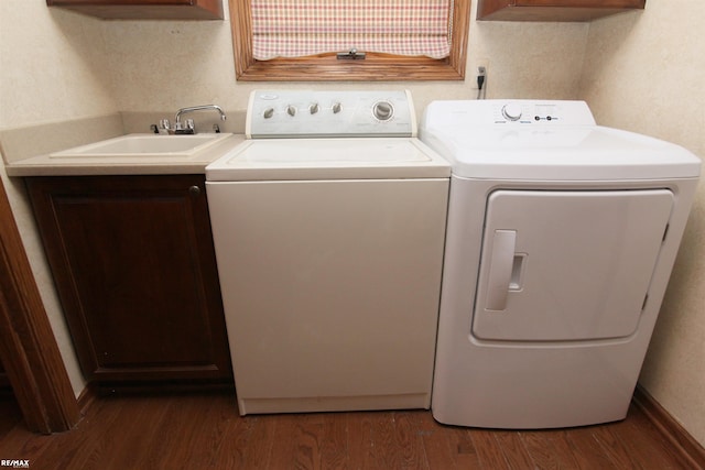 clothes washing area with cabinet space, washer and clothes dryer, a sink, and wood finished floors