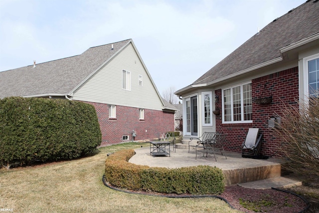 back of property featuring roof with shingles, a patio, a lawn, and brick siding