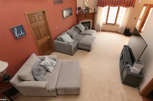 living area with carpet floors, baseboards, visible vents, and a glass covered fireplace