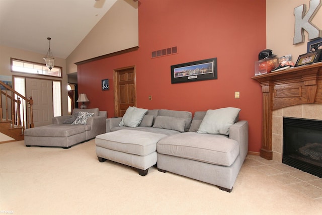 living area with carpet flooring, a fireplace, high vaulted ceiling, stairs, and visible vents