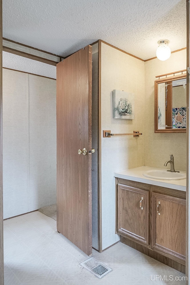 bathroom with a textured ceiling, visible vents, and vanity