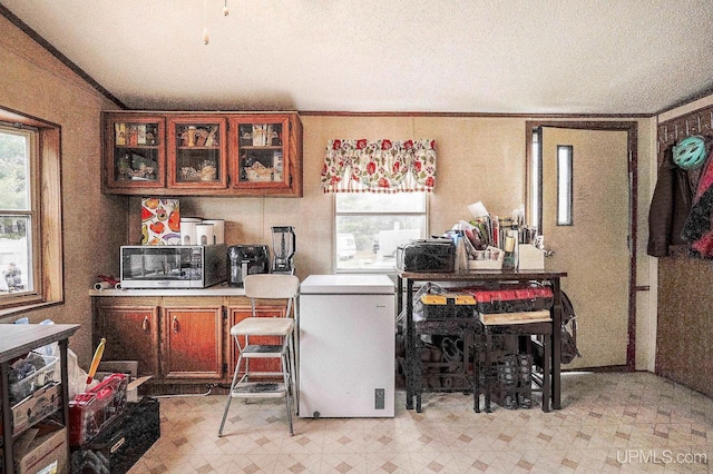 kitchen with light countertops, stainless steel microwave, white fridge, light floors, and glass insert cabinets