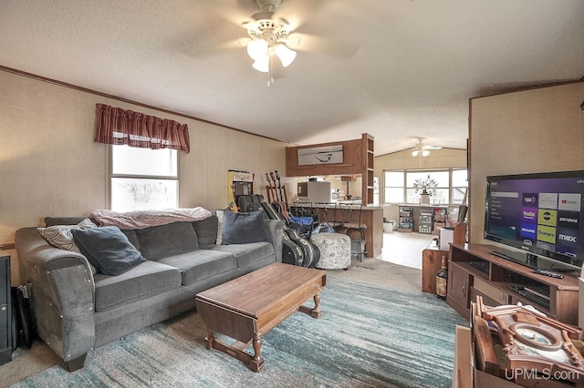 living room with crown molding, carpet floors, a textured ceiling, a ceiling fan, and lofted ceiling