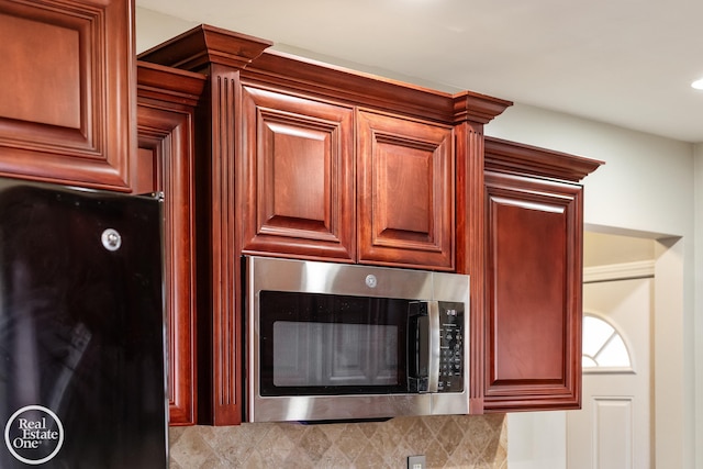 interior details with stainless steel microwave, reddish brown cabinets, and freestanding refrigerator