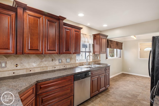 kitchen with freestanding refrigerator, baseboards, tasteful backsplash, a sink, and dishwasher