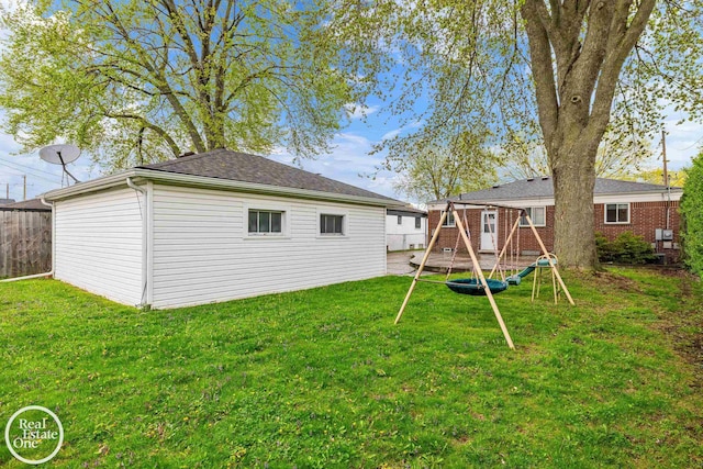 rear view of property featuring a yard, fence, and an outbuilding
