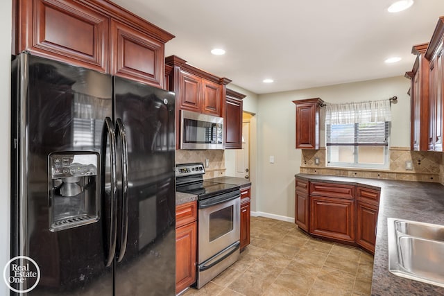 kitchen with backsplash, dark countertops, a sink, stainless steel appliances, and recessed lighting