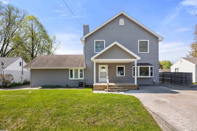 traditional home featuring covered porch, fence, a chimney, and a front yard