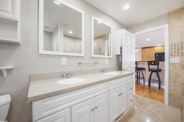 full bathroom with a sink, recessed lighting, toilet, and double vanity
