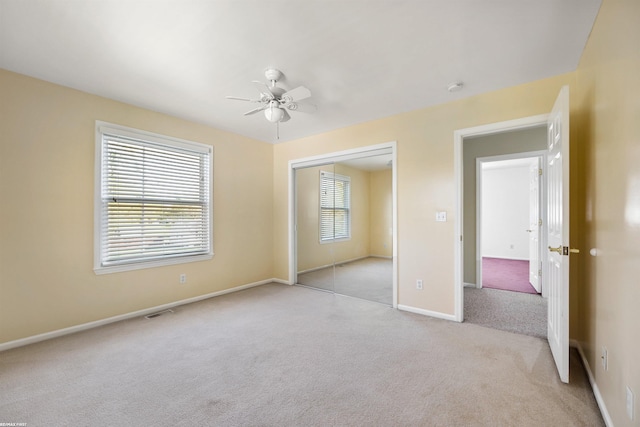 unfurnished bedroom featuring ceiling fan, light colored carpet, baseboards, visible vents, and a closet