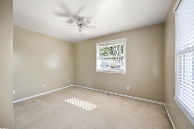 empty room featuring light colored carpet, baseboards, ceiling fan, and visible vents