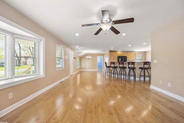 living area with light wood-style floors, baseboards, ceiling fan with notable chandelier, and recessed lighting