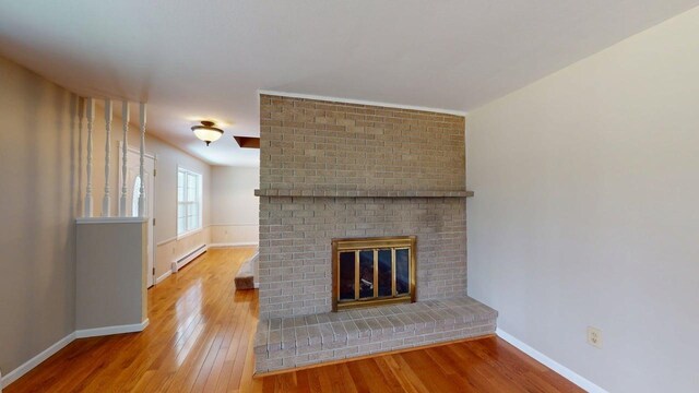 unfurnished living room featuring baseboards, a baseboard heating unit, and hardwood / wood-style flooring
