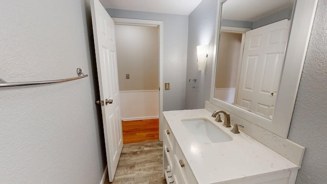 bathroom with a textured wall, wood finished floors, and vanity