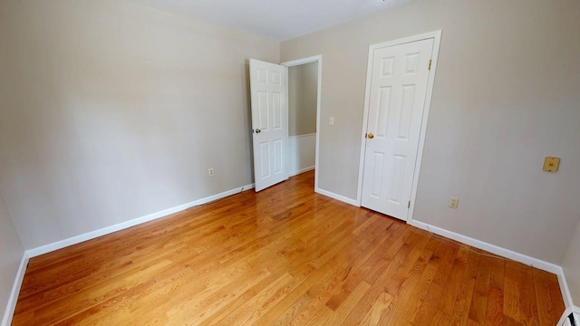 spare room with baseboards and light wood-style floors