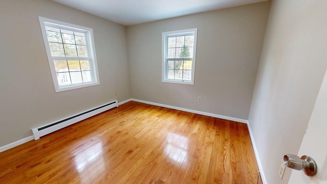 empty room with baseboards, light wood-style flooring, and a baseboard radiator