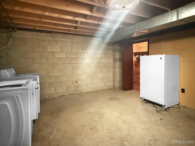 unfinished below grade area featuring freestanding refrigerator and independent washer and dryer