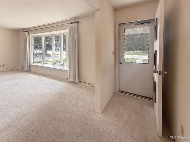 unfurnished room with plenty of natural light, a baseboard radiator, and carpet