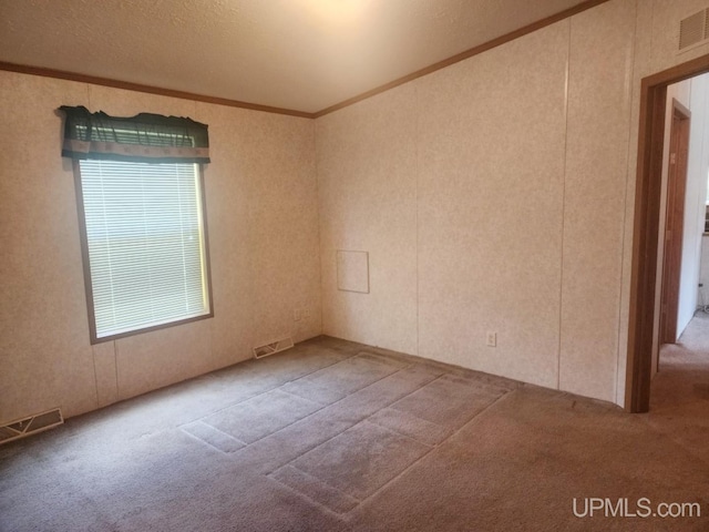 unfurnished room featuring visible vents, carpet flooring, and ornamental molding