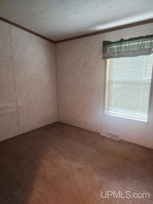 carpeted spare room featuring crown molding, a textured ceiling, and visible vents