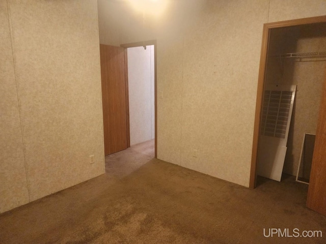 interior space featuring carpet flooring, a heating unit, and a closet