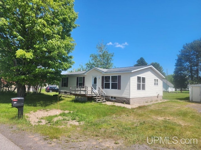 manufactured / mobile home featuring a wooden deck and a front lawn