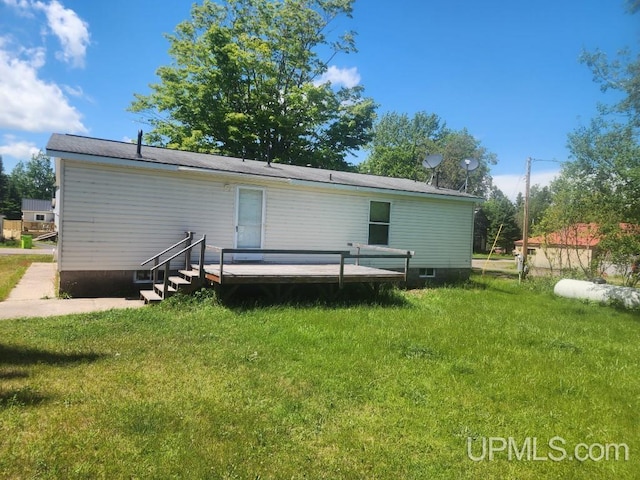 rear view of house featuring a wooden deck and a yard