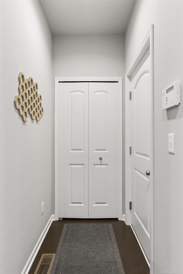 doorway featuring baseboards, visible vents, and dark wood-type flooring