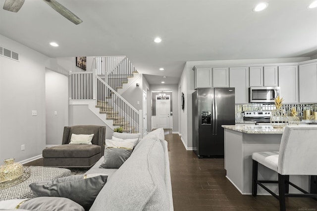 living room featuring dark wood-style flooring, visible vents, stairway, baseboards, and recessed lighting