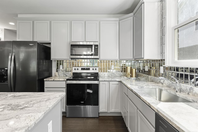 kitchen with dark wood-style flooring, stainless steel appliances, a sink, and tasteful backsplash