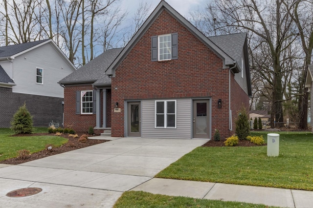 traditional home with brick siding, a front lawn, roof with shingles, and concrete driveway