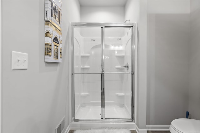 bathroom with baseboards, a stall shower, toilet, and visible vents